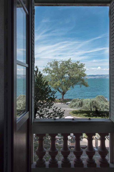 Fenêtre du studio ouverte sur le lac Léman et le balcon à balustres de la résidence